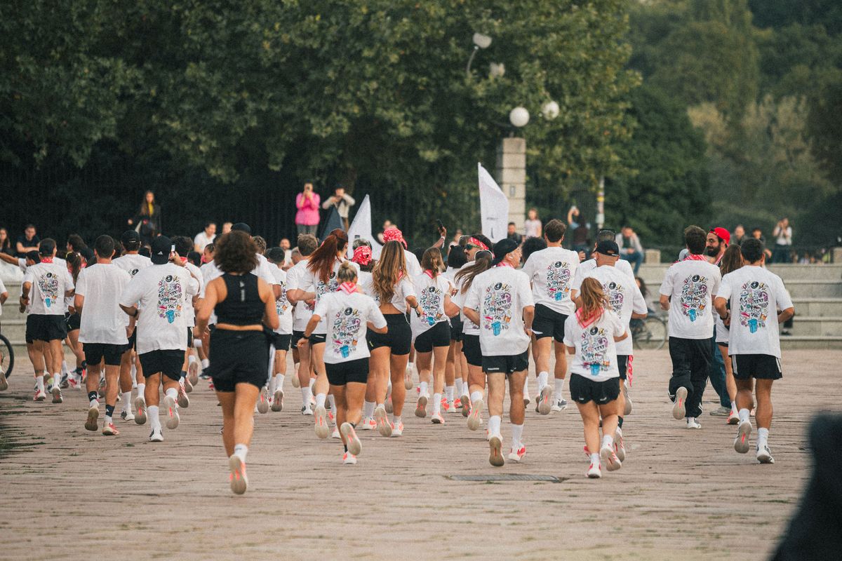 A large group of runners in white tees setting off together