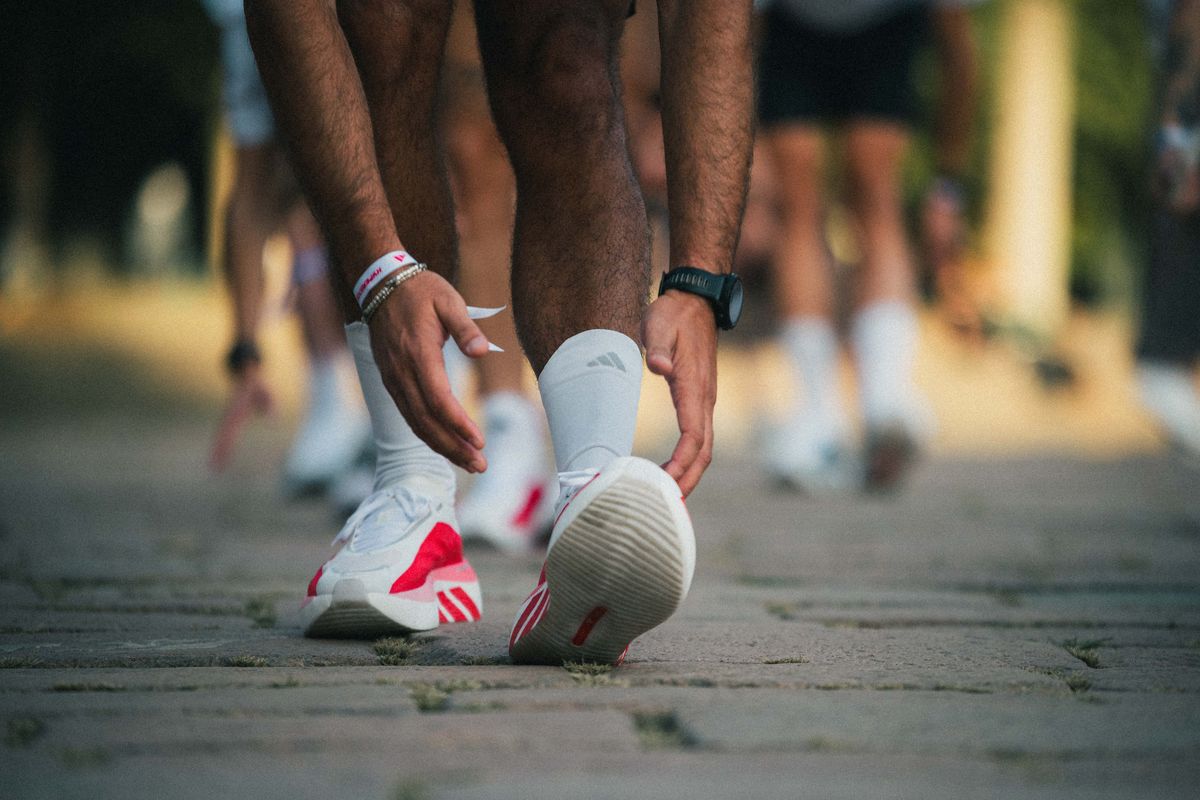 A runner tying an adidas shoe before the start