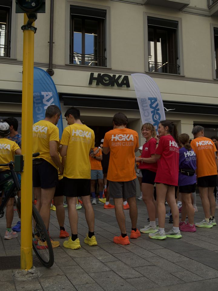 Runners in yellow, orange and red HOKA Run Club tees gathered outside the HOKA store