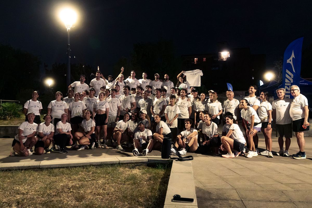 The whole group in white Mizuno Run Club tees after the run, with a Mizuno flag behind