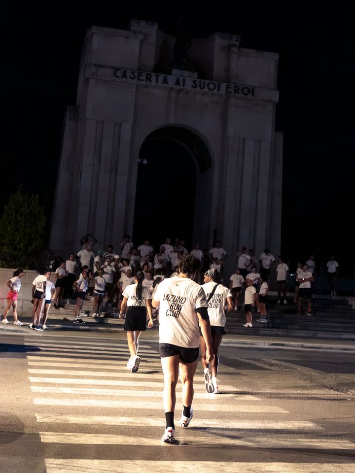 Runners crossing towards the war memorial arch in Caserta, where the group is gathered on the steps