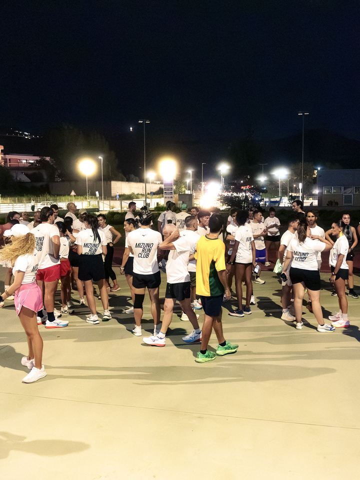 Runners in Mizuno Run Club tees warming up under floodlights